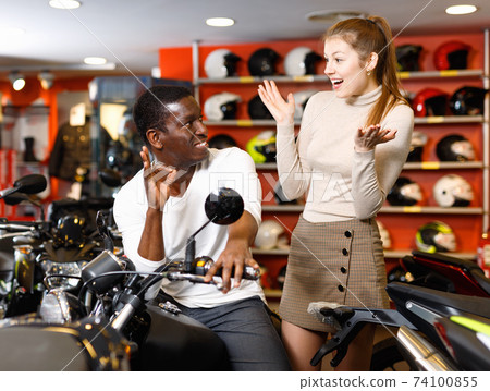 Happy young couple satisfied with choice in modern motorcycle salon 74100855