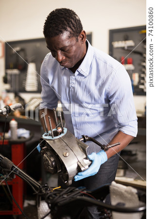 Portrait of afro american man master who is repairing motobike Portrait of afro american man master who is repairing motobike 74100860
