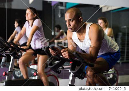 Man ride stationary bike in fitness club Man ride stationary bike in fitness club 74100943