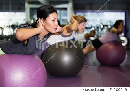Females working out with aerobic ball in modern gym 74100949