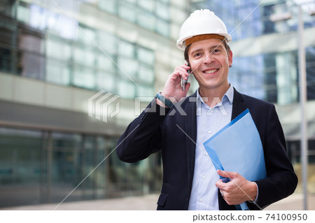 Man in helmet working with documents Man in helmet working with documents 74100950