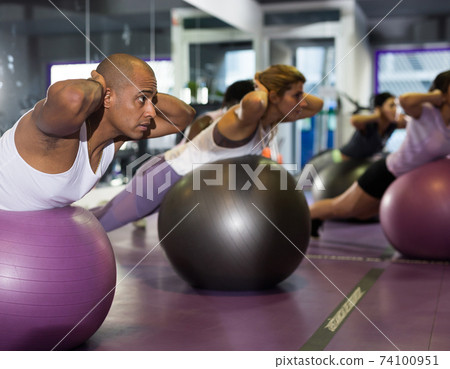 Young man doing exercises with fitness ball Young man doing exercises with fitness ball 74100951