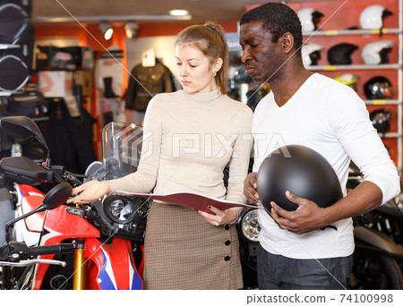 Happy shopping assistant helping male customer Happy shopping assistant helping male customer 74100998