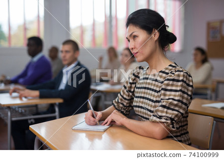 Interested adult korean woman on lesson in school auditorium Interested adult korean woman on lesson in school auditorium 74100999