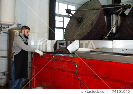 Worker controlling crushing of olives Worker controlling crushing of olives 74101040