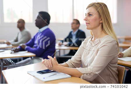 Adult woman studying with colleagues at classroom Adult woman studying with colleagues at classroom 74101042