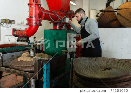 Man applying olive paste to fiber mats Man applying olive paste to fiber mats 74101050