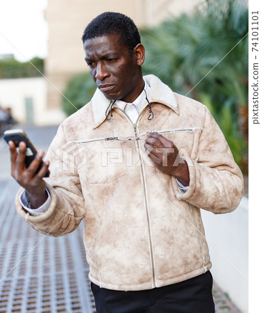 Man in overcoat using smartphone 74101101
