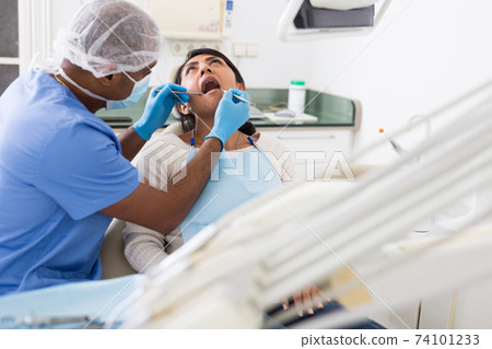 Dentist checking teeth of patient woman sitting in medical clinic 74101233