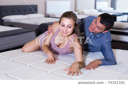 Young couple choosing and lying at matress Young couple choosing and lying at matress 74101391