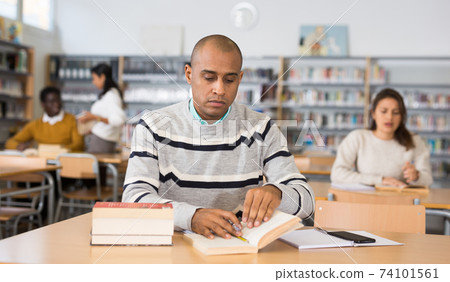 Young adult man studying in public library Young adult man studying in public library 74101561