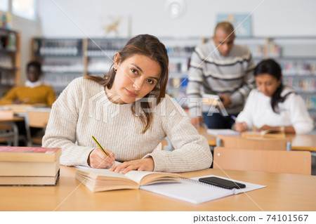 Young adult woman studying in public library Young adult woman studying in public library 74101567