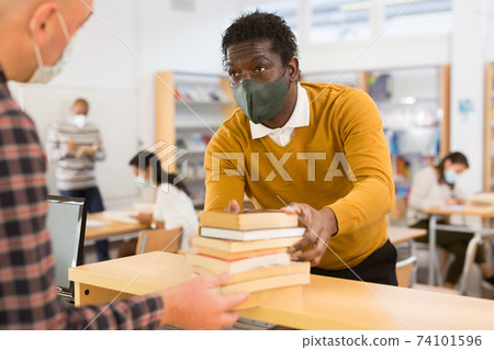 African American adult in protective mask visiting public library African American adult in protective mask visiting public library 74101596