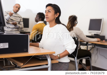 Interested hispanic woman working on computer in library Interested hispanic woman working on computer in library 74101679