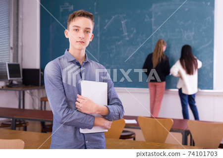Portrait of guy student holding notebook in auditorium Portrait of guy student holding notebook in auditorium 74101703
