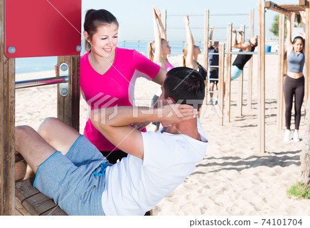 People leading healthy lifestyle, doing exercises on ocean beach at daytime People leading healthy lifestyle, doing exercises on ocean beach at daytime 74101704