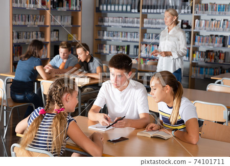 Students brainstorming in teams in library 74101711