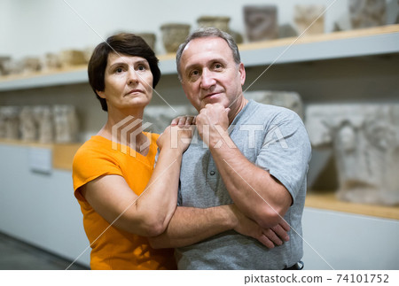 Portrait of couple who is looking at the exposition in historical museum. Portrait of couple who is looking at the exposition in historical museum. 74101752