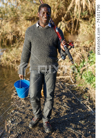 Fisherman holding rod and bucket 74101796