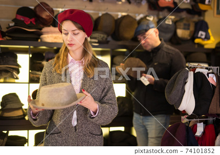 Customers choosing new hats in shop Customers choosing new hats in shop 74101852