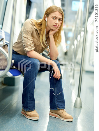 Upset girl in headphones sitting in a subway car Upset girl in headphones sitting in a subway car 74101856