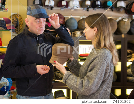 Couple choosing together hat in shop Couple choosing together hat in shop 74101862