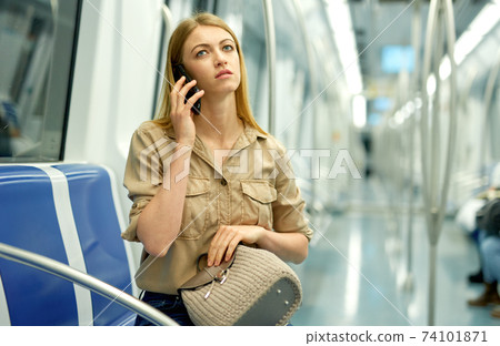 Nice girl speaks on the mobile phone in the subway train Nice girl speaks on the mobile phone in the subway train 74101871