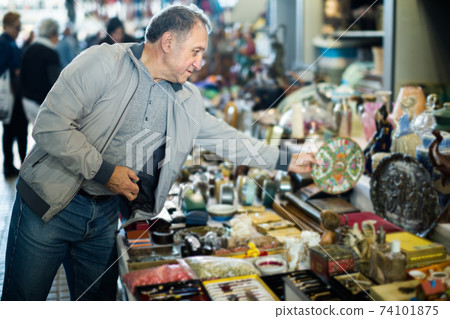 Mature man is choosing old things at the fleamarket Mature man is choosing old things at the fleamarket 74101875