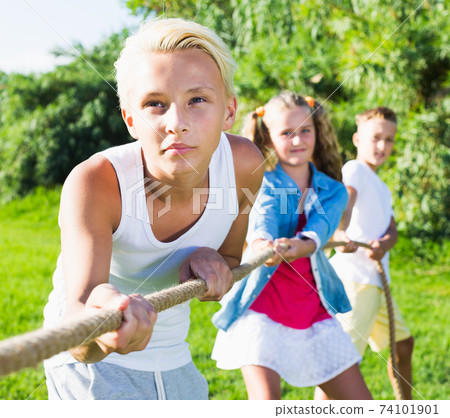 Children playing tug of war outdoors 74101901