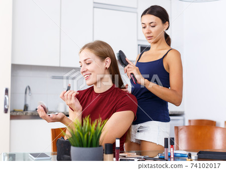 Two modern girls applying make up 74102017