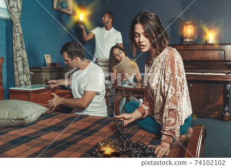 Friends looking at wooden rosary in quest room 74102102