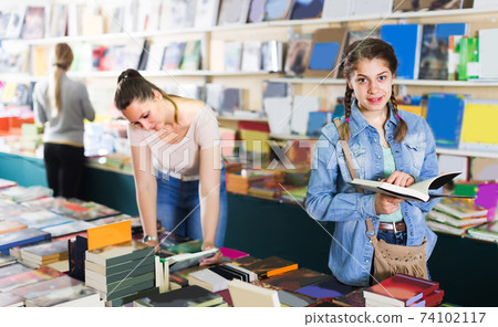 Smiling teenage girl is flipping books Smiling teenage girl is flipping books 74102117