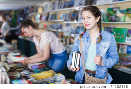 Young girl holding chosen book in hands Young girl holding chosen book in hands 74102118