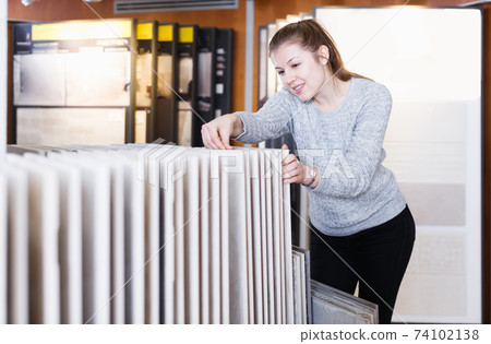 Portrait of young woman choosing ceramic tile 74102138
