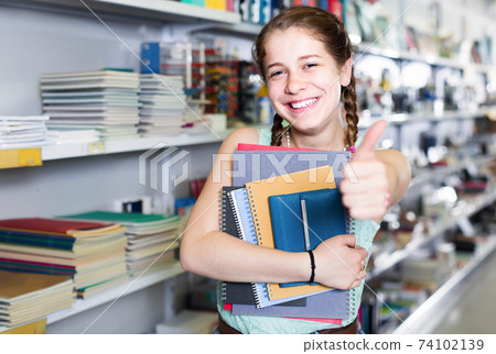 teenager buying different products in stationery shop 74102139