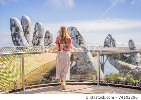 Young woman tourist at Famous tourist attraction - Golden bridge at the top of the Ba Na Hills, Vietnam 74102280