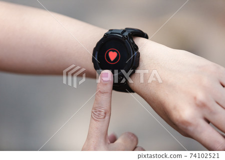 close up hand of woman point finger at smartwatch checking measuring heart rate after exercise. 74102521