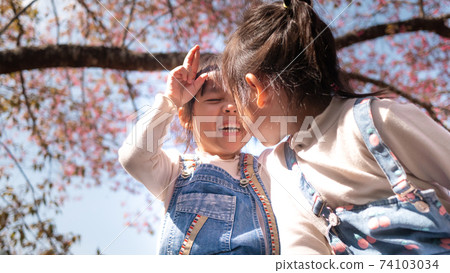 Happy two siblings girls enjoying with nature in the park on sunshine day in springtime. 74103034