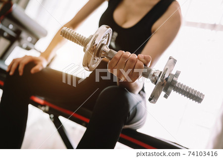 Determined woman losing weight at home and exercising with dumbbells. Sport and recreation concept. Beautiful woman 74103416