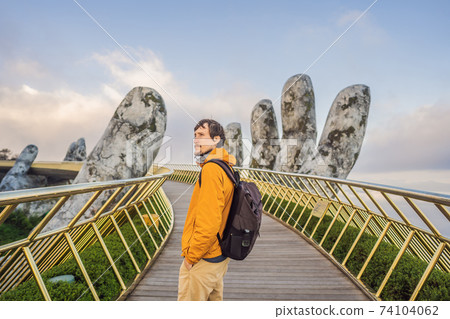 Young man tourist at Famous tourist attraction - Golden bridge at the top of the Ba Na Hills, Vietnam Young man tourist at Famous tourist attraction - Golden bridge at the top of the Ba Na Hills, Vietnam 74104062