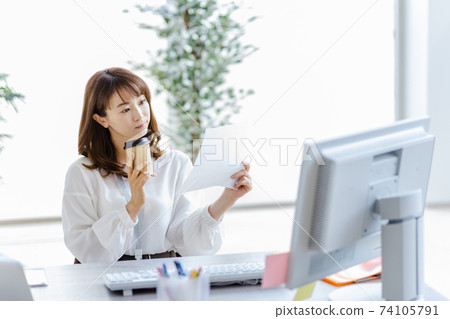 A woman at desk work who leans her head looking at paper materials A woman at desk work who leans her head looking at paper materials 74105791