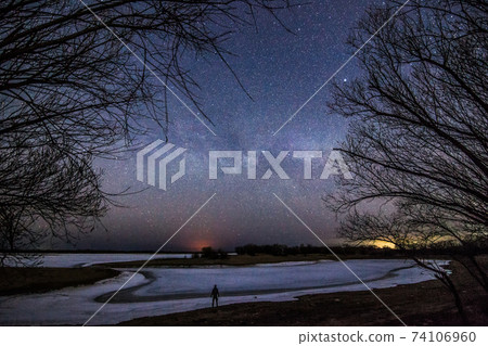 Man at the river bank under starry sky and milky way Man at the river bank under starry sky and milky way 74106960