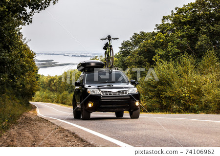 Black crossover with a bicycle and roof box at roof rack Black crossover with a bicycle and roof box at roof rack 74106962