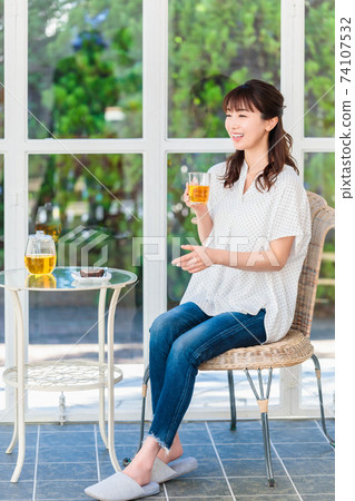 A woman relaxing by drinking tea by the window A woman relaxing by drinking tea by the window 74107532