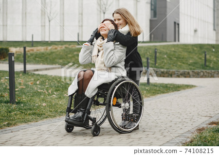 Mother in a wheelchair with hre daughter Mother in a wheelchair with hre daughter 74108215