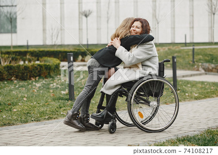 Mother in a wheelchair with hre daughter Mother in a wheelchair with hre daughter 74108217