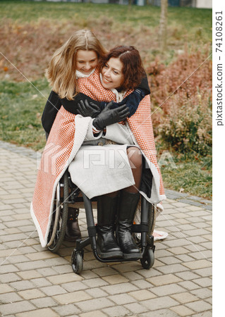 Mother in a wheelchair with hre daughter Mother in a wheelchair with hre daughter 74108261