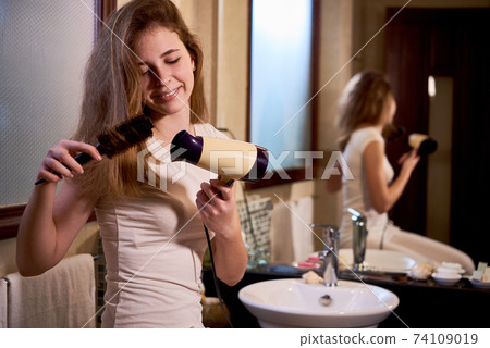 Teenage girl blowing out hair 74109019