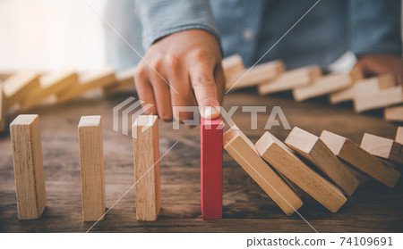 close-up hand The hand of a businessman who is stopping or preventing a falling block.Risk protection concept,Eliminating the risk 74109691