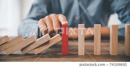 close-up hand The hand of a businessman who is stopping or preventing a falling block.Risk protection concept,Eliminating the risk 74109692